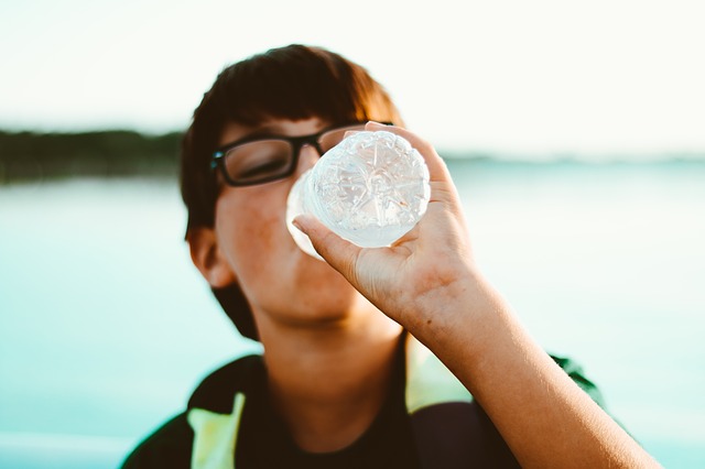 Chico bebiendo una botella de plástico de agua